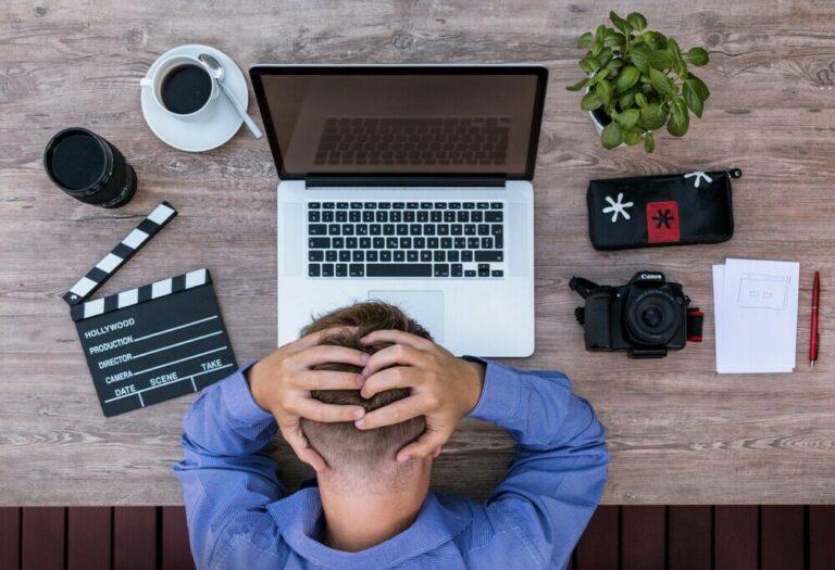 writer is sitting at his desk with his hands clasped behind his head down.