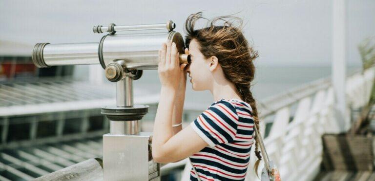 girl looking through a telescope