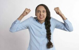 A woman with her hands up with clenched fists frustrated looking