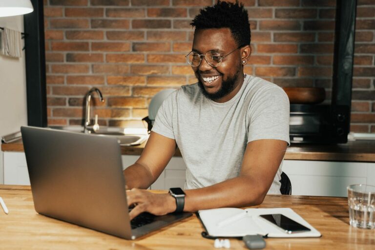 A writer sitting at a table typing on his laptop
